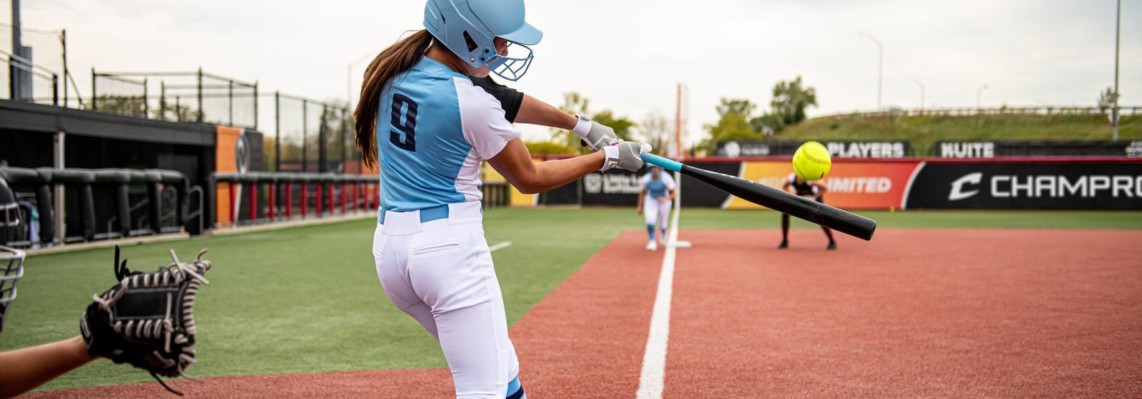 Champro fastpitch uniforms in play: BS80 jersey, BP11K pant, AS3 socks and an HXFPM fastpitch mask. Manufacturer photography.